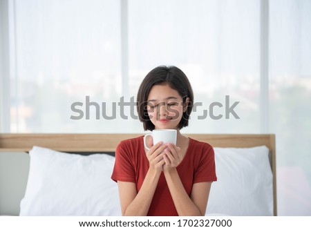 Woman with sleepwear wake up on the bed at the bedroom with morning coffee on hand 