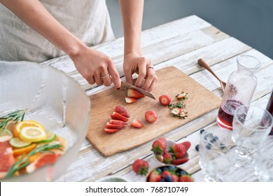 Woman Slicing Fresh Strawberries To Add To The Fruit Punch Cocktail Mocktail For Fourth Of July Party