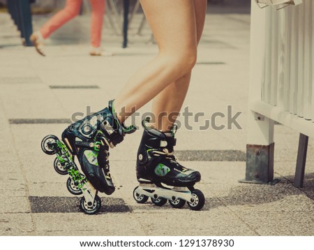 Woman slim legs wearing roller skates standing outside. Sport activity objects concept.