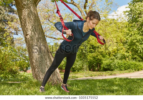 Woman sling\
training or suspension training at\
park