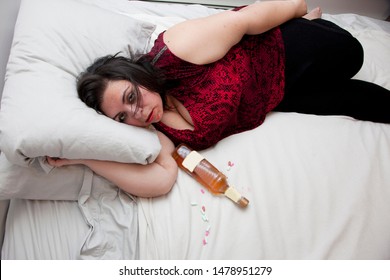 Woman Sloppy Or Drunk In Bed With A Bottle And Pills With Copy Space On Bed 