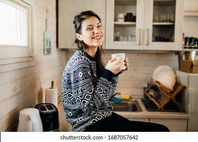 Woman in small kitchen drinking morning coffee.Happiness.Tiny house.First property.Small apartment interior design.Minimalism.Moving in.Living alone.Charming trailer house