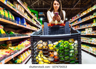 Woman With Smartphone In Store. Grocery Shopping. Gadgets And Shopping.