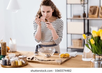 Woman Smelling Essential Oil While Preparing Organic Cosmetics In A Kitchen