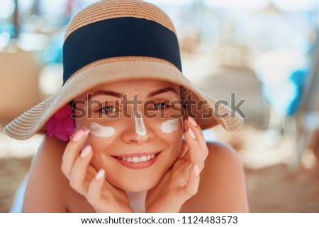 
Woman smile applying sun cream  on face. Skincare. Body Sun protection. sunscreen. Female in hat smear  moisturizing lotion on skin.