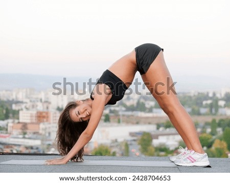 Woman, smile and warm up on rooftop for yoga, downward facing dog pose and urban city of Cape Town. Person, wellness and stretching body for balance to improve flexibility, mobility and peace of mind