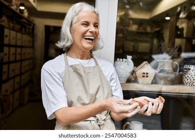 A woman smiles brightly while shaping clay in her charming artisan workshop surrounded by art. - Powered by Shutterstock