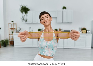 A woman smiles as she stretches with a yellow resistance band in a modern apartment. - Powered by Shutterstock