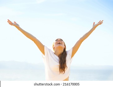Woman smiling arms raised up to blue sky, celebrating freedom. Positive human emotions, face expression feeling life perception success, peace of mind concept. Free Happy girl on beach enjoying nature