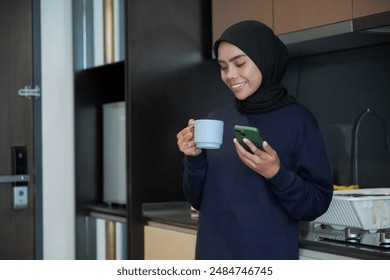 A woman is smiling and holding a cup of coffee while holding a cell phone. Concept of relaxation and enjoyment, as the woman is taking a break from her daily routine to enjoy a warm beverage - Powered by Shutterstock