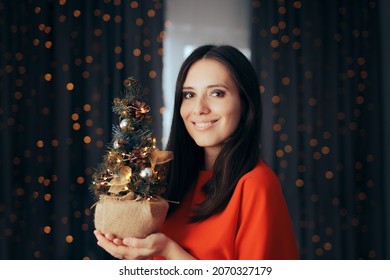 
Woman Smiling Holding A Small Christmas Tree Decoration. Party Host With Miniature Decorated Eco-friendly Tree 
