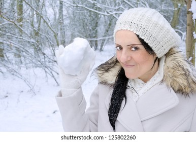 Woman Smiling Holding Snowball In Snow Covered Forest