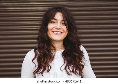 Woman smiling with perfect smile and white teeth over urban wall. Plus size model - Powered by Shutterstock