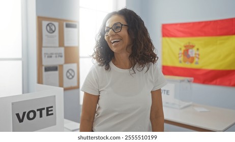 Woman smiling at a polling station in spain with a spanish flag in the background, signified by the vote sign and electoral posters displayed indoors in a well-lit room. - Powered by Shutterstock