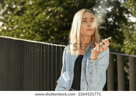 Woman smoking cigarette near railing outdoors. Space for text