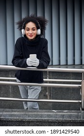 Woman With A Smug Look On Her Face Texting On A White Phone While Taking A Break Near The Building