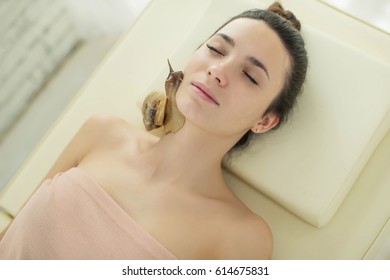 A woman with a snail on her face - Shutterstock ID 614675831