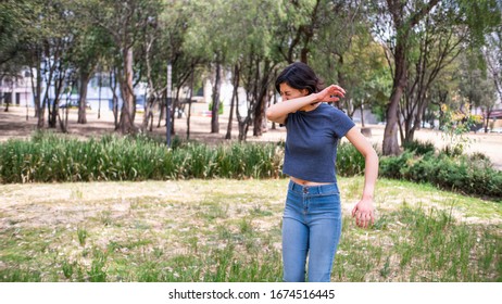 Woman Sneezing Into Elbow Outdoors Public Park