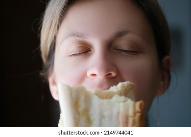 Woman sniffing delicious fragrant piece of white bread. Fresh bakery concept