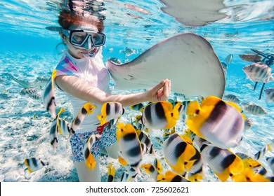 Kvinna snorkling i klara tropiska vatten bland färgglada fiskar