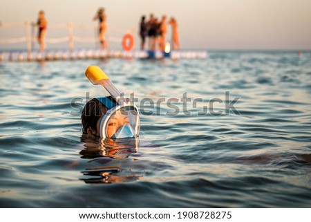 woman snorkeling in full-face snorkeling mask in the red sea on sunset