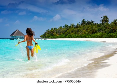 Woman With Snorkeling Gear Running Into The Turquoise, Tropical Waters Of The Maldives