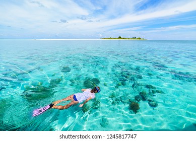 Woman snorkeling on coral reef tropical caribbean sea, turquoise blue water. Indonesia Wakatobi archipelago, marine national park, tourist diving travel destination