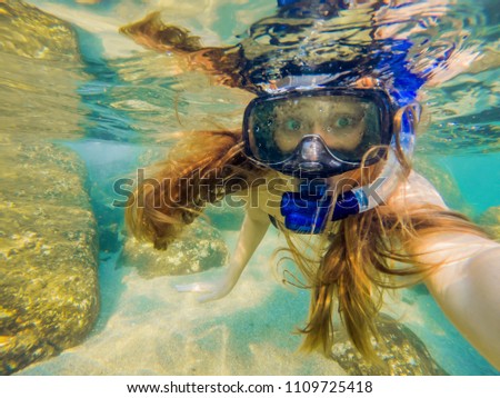Woman snorkeling in tropical waters in front of exotic island.