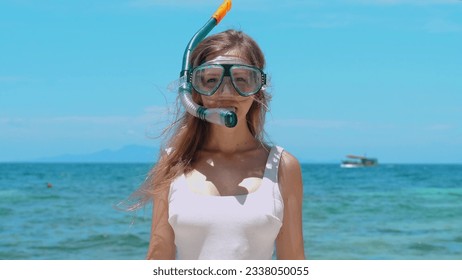 Woman snorkeling in turquoise sea, taking off mask. Female enjoying snorkeling in blue ocean, removing mask. Concept of active summer vacation and underwater exploration. - Powered by Shutterstock