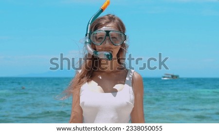 Woman snorkeling in turquoise sea, taking off mask. Female enjoying snorkeling in blue ocean, removing mask. Concept of active summer vacation and underwater exploration.
