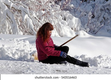 A Woman Is With The Snow Shovel Fallen Down. Wintery Accident