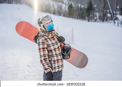 Woman Snowboarder On A Sunny Winter Day At A Ski Resort Wearing A Medical Mask During COVID-19 Coronavirus