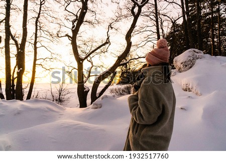 woman in snowy park watch sunset outdoor.back view