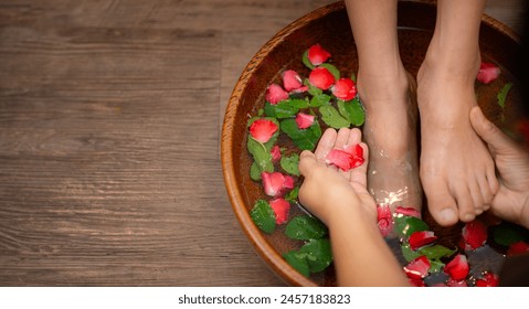 Woman soaks her feet in a bowl with rose flower petals. Foot Spa Concept - Powered by Shutterstock