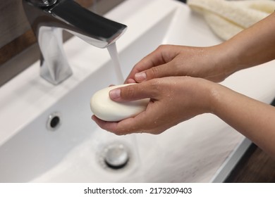 Woman With Soap Bar Washing Hands In Sink, Closeup