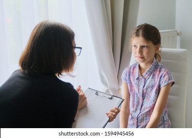 Woman Social Worker Psychologist Talking To Girl Child In Office, Female Counselor Taking Notes In Clipboard. Children Mental Health