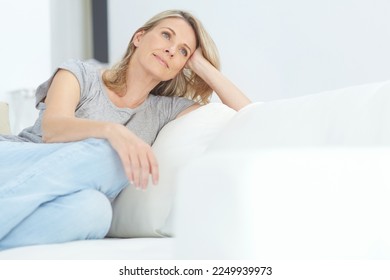 Woman, sofa and relax for thinking, rest and memory in home living room for peace, quiet and mindfulness. Mature lady, couch and sitting for calm reflection in house, lounge or apartment in Australia - Powered by Shutterstock