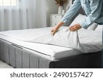 Woman with soft orthopedic mattress making bed at home, closeup