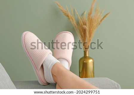Woman in soft slippers lying on sofa at home