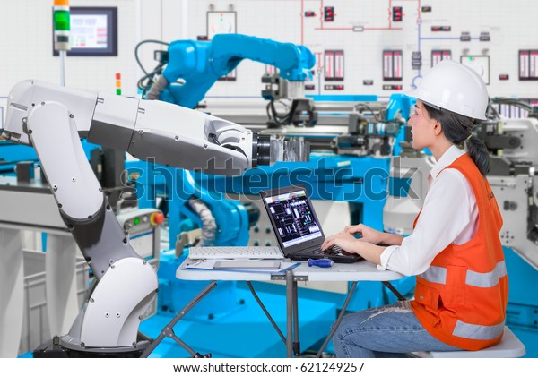 Woman software engineers developing\
automated robotic in production line, Industry 4.0\
concept