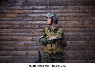 Woman Soldier Using Tablet Computer  Against Old Wooden  Wall In Camp