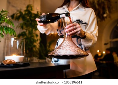 woman sommelier decanting a red wine