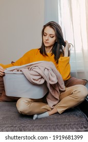 Woman Sorting Old Clothes Into White Container With Recycle Sign. Green Recycling Sign On White Container. Woman Throwing Out Old Clothes.