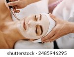 Woman, spa and face mask with brush applicator, pamper weekend and skincare wellness with client. Facialist, treatment and skin rejuvenation or pore tightening, eyes closed and facial beauty or above