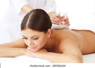 Woman in spa getting massage with herbal balls