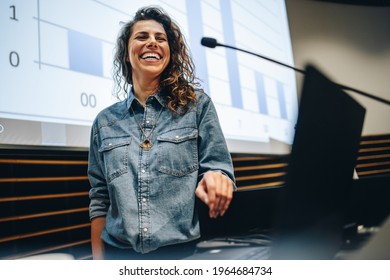 Woman Speaking At A Business Summit And Smiling. Successful Female Presenter Standing At The Podium Of A Business Conference.