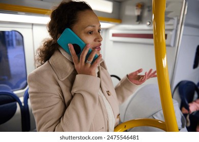 A woman speaking on her smartphone while riding a bus. She wears a winter coat and appears to be engaged in the conversation. Commuting and public transportation context. - Powered by Shutterstock