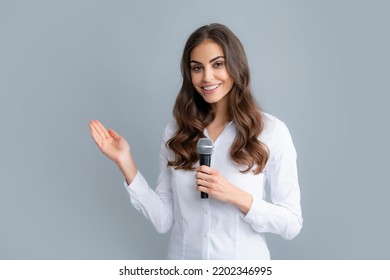 Woman Speech, Business Woman Holding A Microphone. Public Speaking With Microphone, Speaker Speech Presentation Concept. Beautiful Stylish Woman Singing Karaoke Isolated Over Gray Background.