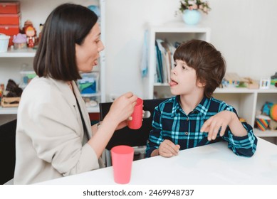 Woman speech therapist helps a child correct the violation of his speech in her office - Powered by Shutterstock