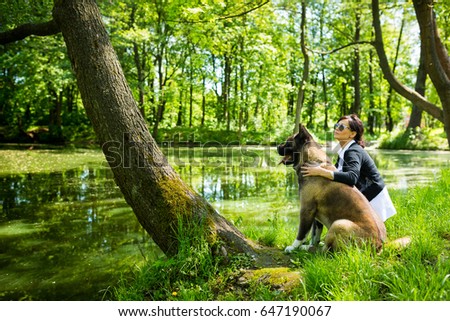 The woman is spending time with American Akita dog near the pond